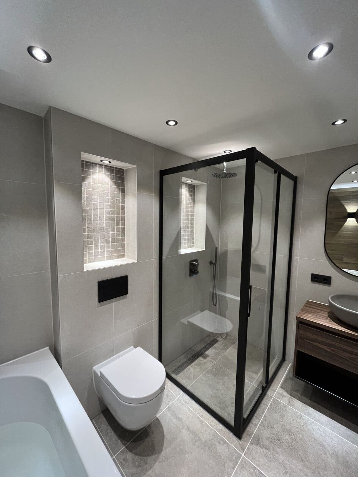 Douchecabine met zwart profiel naast een hangtoilet